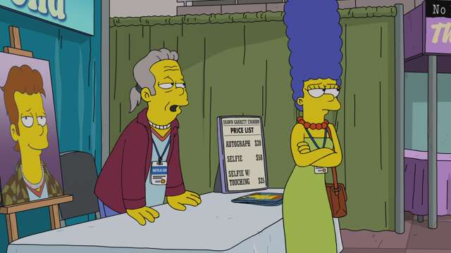 Marge se tient devant la table de dédicaces où Shawn Garrett Evanson est assis, à la convention.
